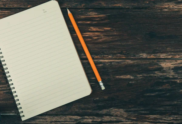 Notepad with yellow pencil placed on old wooden floor vintage style