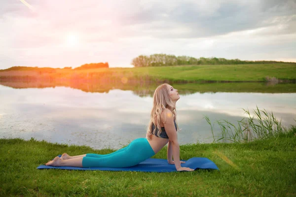 Güzel bir atletik sarışın kız portresi nişanlı Yoga bir göl üzerinde yakın çekim, sağlıklı bir yaşam tarzı destekler