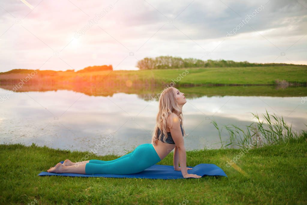 Portrait of a beautiful athletic blonde girl engaged in yoga on a lake, close-up, It supports a healthy lifestyle