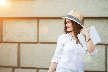 Paketleri ile sokakta yürürken bir mağazadan şapkalı gülümseyen güzel esmer kız.