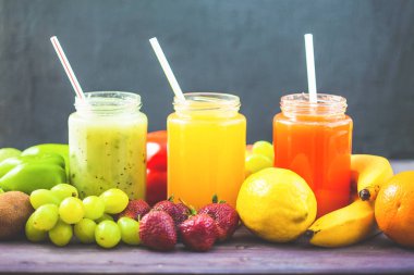 taze sıkılmış meyve suyu, smoothies sarı turuncu yeşil mavi muz limon elma portakal kivi üzüm çilek koyu ahşap arka plan kopya alanı üzerinde
