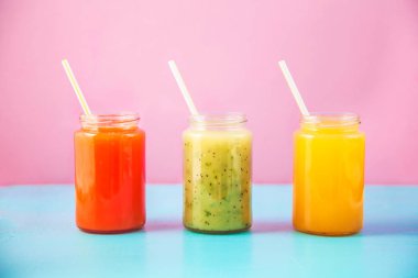 taze sıkılmış meyve suyu, turuncu parlak mavi ve pembe arka plan üzerinde kopya alanı yeşil smoothies sarı.