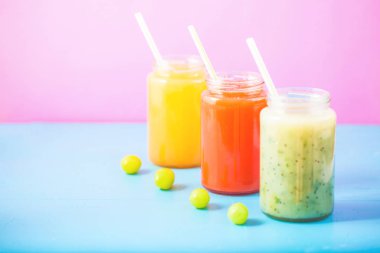 taze sıkılmış meyve suyu, smoothies sarı turuncu yeşil üzüm parlak mavi ve pembe kopya alanı arka plan.