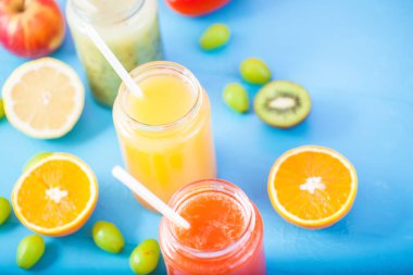taze sıkılmış meyve suyu, smoothies sarı turuncu yeşil mavi muz limon elma portakal kivi üzüm çilek parlak mavi arka plan kopya alanı üzerinde