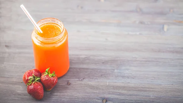 freshly squeezed fruit juice, smoothies orange orange strawberry on a dark wooden background Copy space.