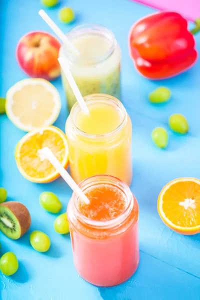 taze sıkılmış meyve suyu, smoothies sarı turuncu yeşil mavi muz limon elma portakal kivi üzüm kadar parlak mavi zemin üzerine yakın çilek.