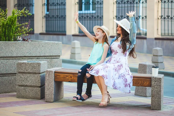 iki kız kardeş, bir güzel esmer kız ve Genç kız yürüyerek şehir, bir bankta oturup ve konuşmak, gülmek ve ellerini dalga