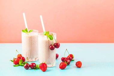 İki bardak süt smoothies kiraz, çilek, muz ve parlak nane ile sağlıklı bir yaşam tarzı kavramı arka plan. Kopya alanı lezzetli ve sağlıklı kilo kaybı için yer.
