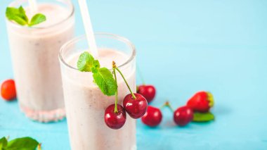 İki bardak süt smoothies kiraz, çilek, muz ve parlak nane ile sağlıklı bir yaşam tarzı kavramı arka plan. Kopya alanı lezzetli ve sağlıklı kilo kaybı için yer.