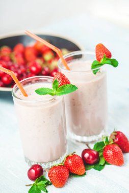 İki bardak süt, çilek, muz, kiraz, parlak beyaz arka plan kavramı sağlıklı yaşam, nane ile dekore edilmiş yapılır smoothies, lezzetli yakın kadar diyet