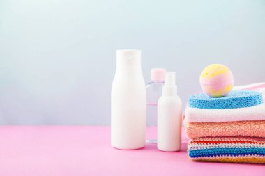banyo aksesuarları - ateşin üzerinde havlu ve şampuanlar, banyo köpüğü, krem, parlak mavi ve pembe arka plan kendiniz için vücut bakım kavramı. Kopya alanı için yer