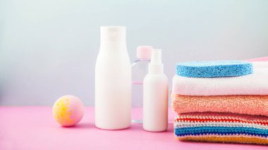 banyo aksesuarları - ateşin üzerinde havlu ve şampuanlar, banyo köpüğü, krem, parlak mavi ve pembe arka plan kendiniz için vücut bakım kavramı. Kopya alanı için yer