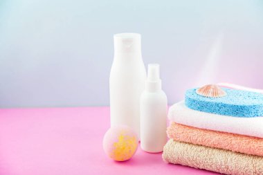 banyo aksesuarları - ateşin üzerinde havlu ve şampuanlar, banyo köpüğü, krem, parlak mavi ve pembe arka plan kendiniz için vücut bakım kavramı. kopya alanı