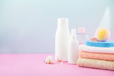 banyo aksesuarları - ateşin üzerinde havlu ve şampuanlar, banyo köpüğü, krem, parlak mavi ve pembe arka plan kendiniz için vücut bakım kavramı. kopya alanı