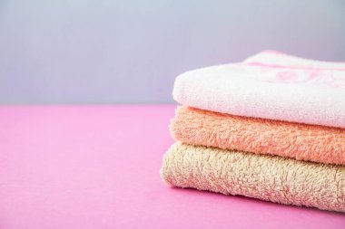 banyo aksesuarları - havlu katlanmış, kendiniz için vücut bakım kavramının bir ışık, parlak mavi ve pembe arka plan üzerine yığılmış. Kopya alanı.