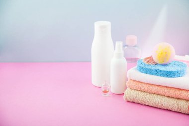 banyo aksesuarları - ateşin üzerinde havlu ve şampuanlar, banyo köpüğü, krem, parlak mavi ve pembe arka plan kendiniz için vücut bakım kavramı. kopya alanı