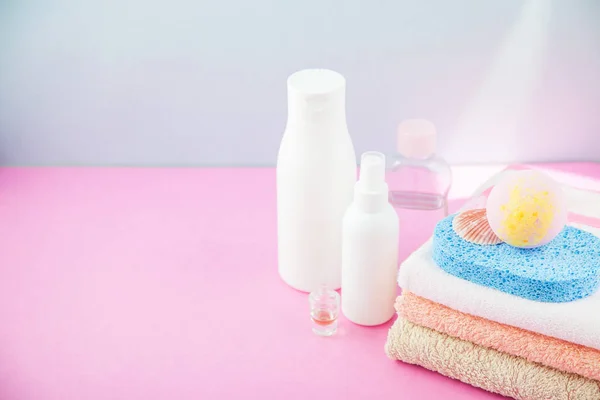 banyo aksesuarları - ateşin üzerinde havlu ve şampuanlar, banyo köpüğü, krem, parlak mavi ve pembe arka plan kendiniz için vücut bakım kavramı. kopya alanı