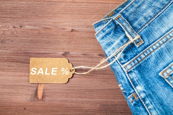 Satış, iskonto, siyah Cuma kavramı etiketi ile ahşap bir zemin üzerine mavi jeans. Boşaltmak üst görünümü.