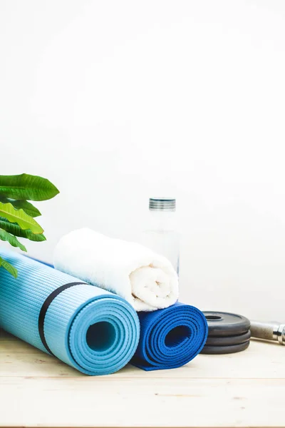 set for sports, a yoga mat, a towel, a dumbbell and a bottle of water on a light background. The concept of a healthy lifestyle Copy space