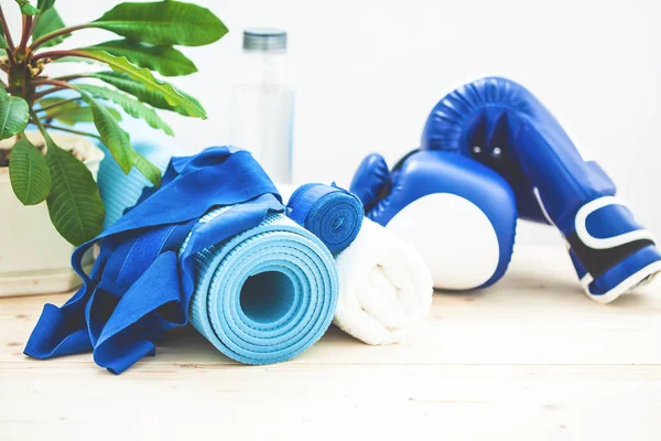 set for sports, a yoga mat, a towel, boxing gloves and a bottle of water on a light background. The concept of a healthy lifestyle