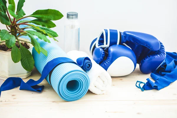 set for sports, a yoga mat, a towel, boxing gloves and a bottle of water on a light background. The concept of a healthy lifestyle.