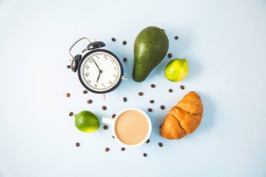 sabah kahve Kupası'nda bir beyaz kruvasan avokado kireç uyanış bir çalar saat kahvaltı neşe, sağlıklı kahvaltı tazelik ile