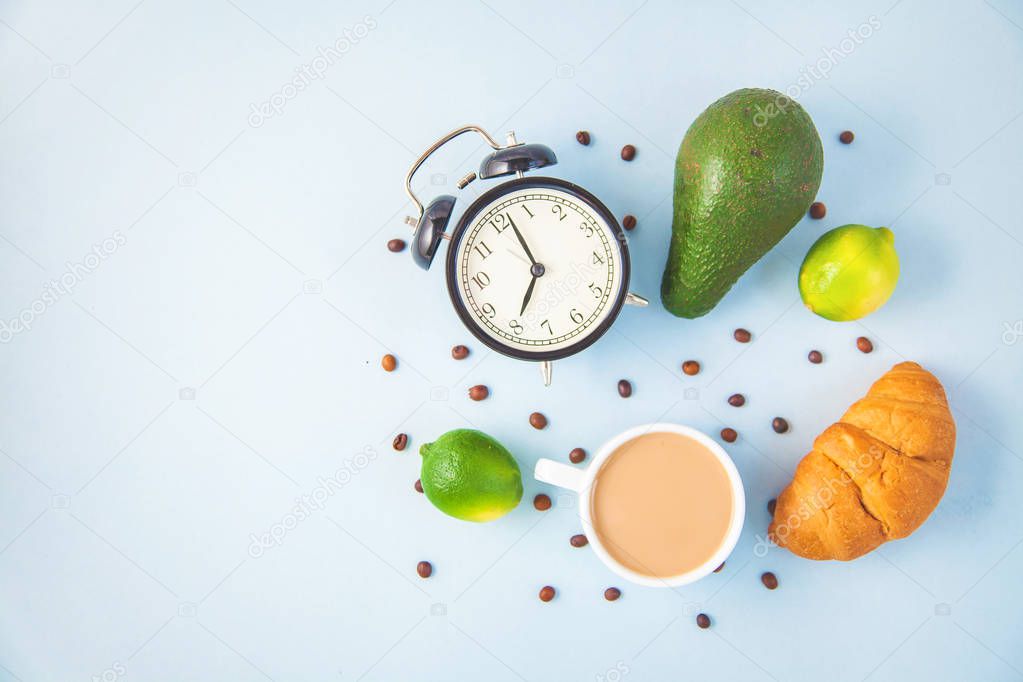 morning breakfast ,coffee in a white cup Croissant Avocado Awakening with an alarm clock Cheerful, healthy breakfast fresh Copy space Top view.