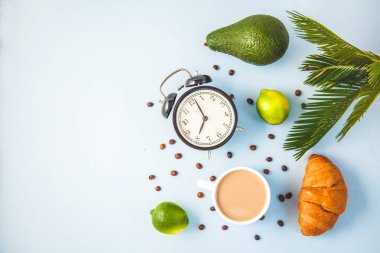 sabah kahvesi bir çalar saat kahvaltı neşe ile hafif bir arka plan uyandırma üzerinde beyaz bir fincan kruvasan avokado kireç, sağlıklı kahvaltı tazelik düz kopya spase yatıyordu..