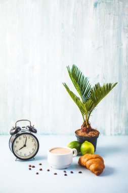 sabah kahvaltı, kahve ateşin üzerinde beyaz bir fincan kruvasan kireç uyanış bir çalar saat neşeli, sağlıklı kahvaltı taze kopya alanı ile arka plan.