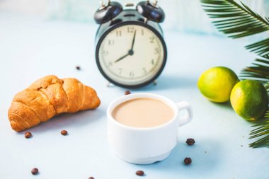 sabah kahvesi bir çalar saat kahvaltı neşe, sağlıklı kahvaltı tazelik yakın-up uyanmak-yukarıya bir ışık zemin üzerine beyaz bir fincan kruvasan kireç