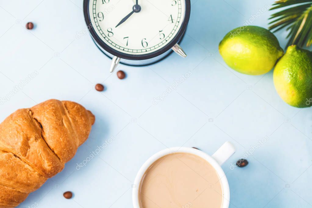 morning breakfast ,coffee in a white cup Croissant Avocado Lime Awakening with an alarm clock Cheerful, healthy breakfast fresh Copy space Top view.