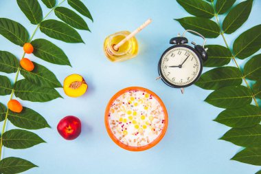 sabah kahvaltı, müsli, meyve, şeftali, tatlım yeşil ile mavi bir arka plan üzerinde bırakır uyanış bir çalar saat düz yatıyordu sağlıklı kahvaltı tazelik ile