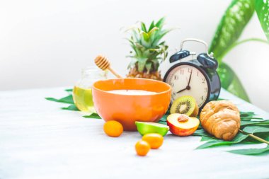 sabah kahvaltı, müsli, meyve, şeftali, bal ve ananas yeşil ışık bir zemin üzerine bırakır uyanış bir çalar saat ile sağlıklı kahvaltı tazelik kopya alanı