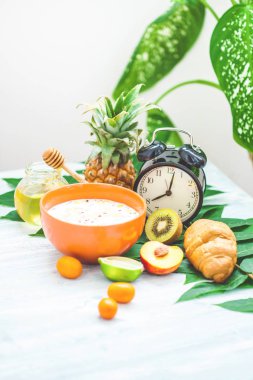 sabah kahvaltı, müsli, meyve, şeftali, bal ve ananas yeşil ışık bir zemin üzerine bırakır uyanış bir çalar saat ile sağlıklı kahvaltı tazelik yakın çekim