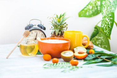 sabah kahvaltı, müsli, meyve, şeftali, bal ve ananas yeşil ışık bir zemin üzerine bırakır uyanış bir çalar saat ile sağlıklı kahvaltı tazelik kopya alanı