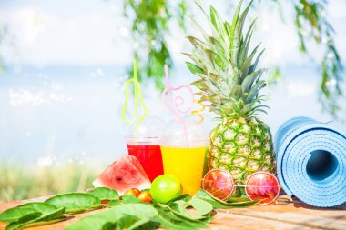 Parlak taze sağlıklı meyve suları, meyve, ananas, karpuz. deniz arka plan üzerinde güneş gözlüğü yoga mat. Summer, dinlenme, sağlıklı yaşam tarzı kopya alanı