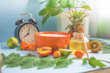 Yararlı sabah kahvaltı, müsli, Closeup meyve şeftali kireç ananas bal fincan kahve ve bir çalar saat üzerinde mavi bir arka plan