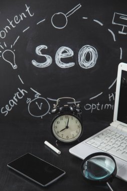SEO arama motoru optimizasyonu kavramı Büyüteç Camı'nı, saat, smartphone bir yazıt tebeşir Seo portre siyah bir zemin üzerine