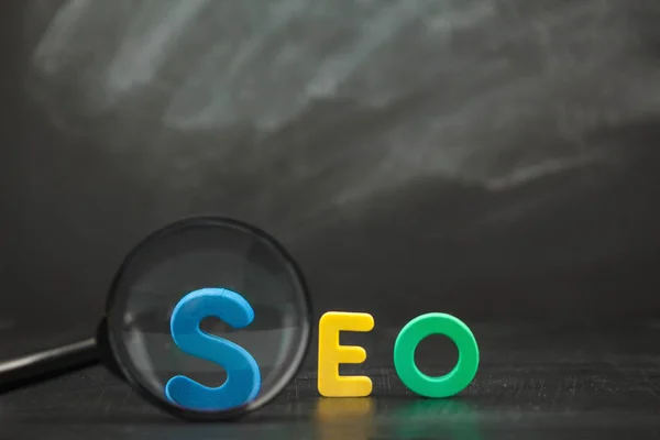 SEO arama motoru optimizasyonu kavramı SEO renk harflerle Büyüteç siyah bir arka plan kopya alanı