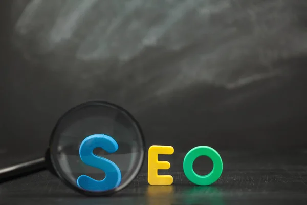 SEO Search engine optimization concept kleur brieven van Seo met vergrootglas op een zwarte achtergrond kopie ruimte Rechtenvrije Stockfoto's