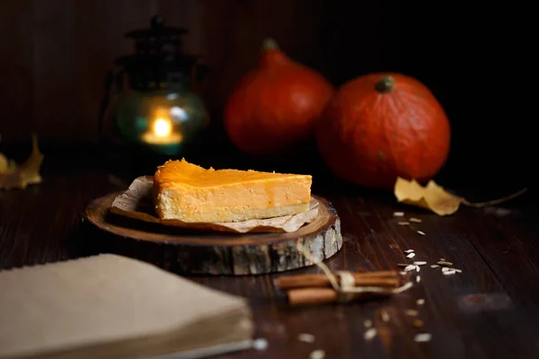 Pumpkin cheesecake, cooked at home, pumpkin, vanilla ,notepad, foliage on a wooden dark table. Autumn and winter cozy concept.