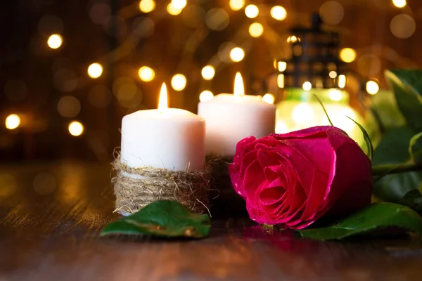 red rose and lantern with lights on a wooden table.