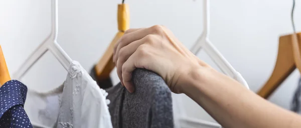 Female hand chooses clothes on a hanger