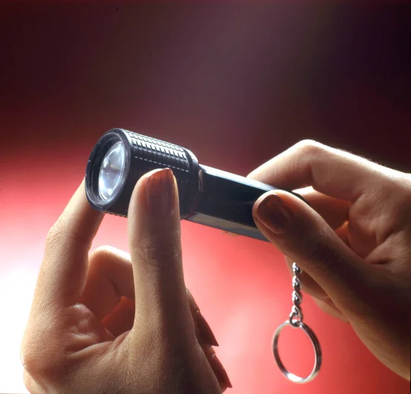 hand model holds a small torch with key holder. close-up