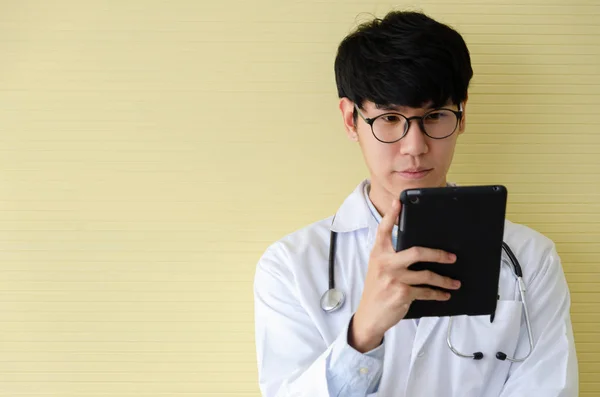 Młody lekarz w białym mundurze patrząc na tablet iPad — Zdjęcie stockowe