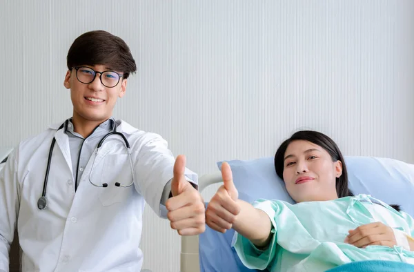 Porträtt Lycklig Kvinnlig Patient Liggande Sjukhussängen Och Manlig Läkare Visar — Stockfoto