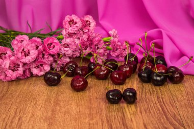 Yaz pembe Karanfil Pembe kumaş arka plan üzerinde bir arka plan üzerinde büyük koyu kırmızı kiraz