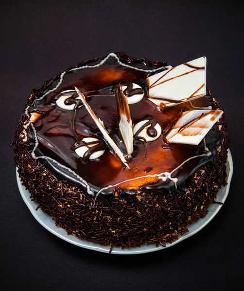 small chocolate cake with frosting and decorations of white chocolate on a black background