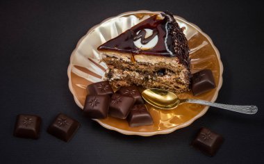 siyah bir zemin üzerine çikolata çinilerin adet sarı inci tabakta çikolatalı pasta kesme bir parçası