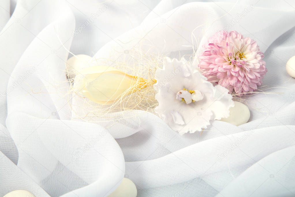 white background of soft fabric lined with folds with spring white freesia and round candies